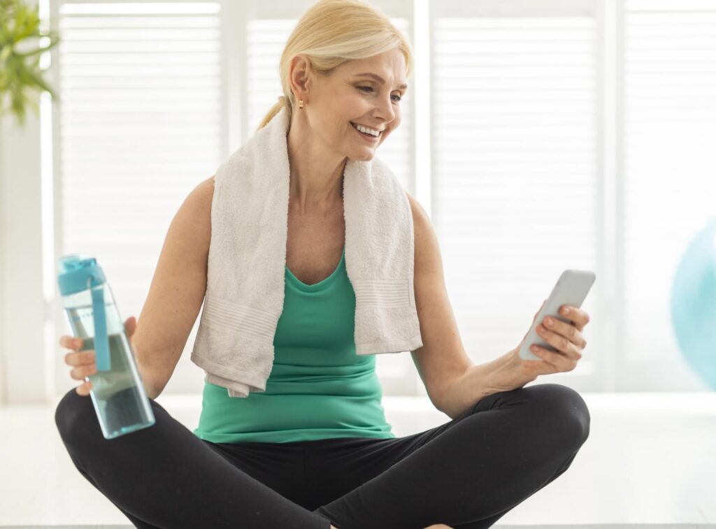 fit-senior-woman-relaxing-on-yoga-mat-with-smartph-2023-11-27-05-22-29-utc@2x